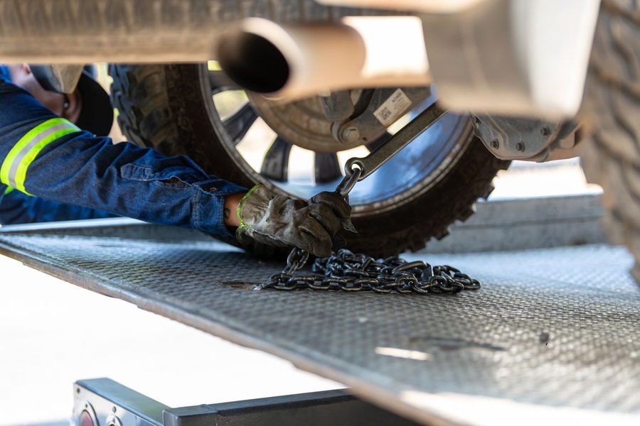 Man fastening a car’s wheel to a tow truck